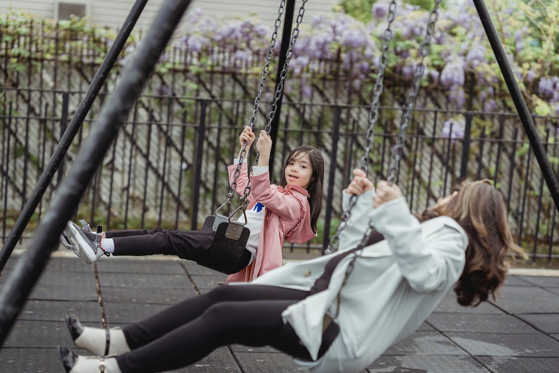 woman and young girl playing in the swing woman and young girl playing in the swing
