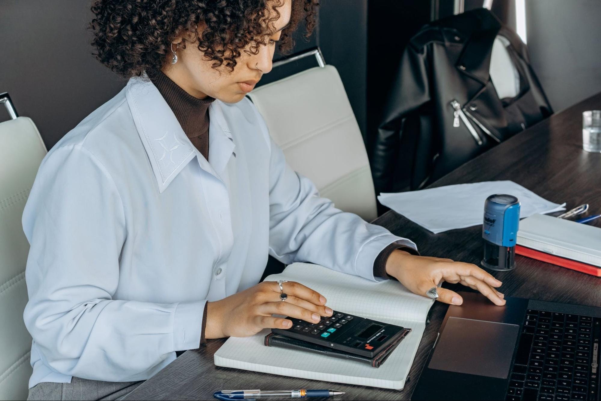 young female employee using a black calculator young female employee using a black calculator
